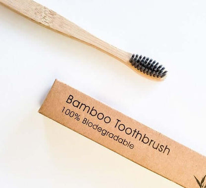 Eco-friendly bamboo toothbrush with activated charcoal bristles and biodegradable packaging.