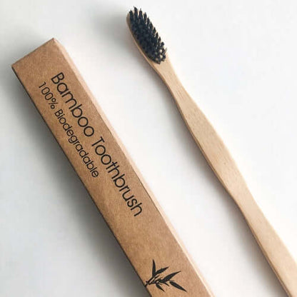 Eco-friendly bamboo toothbrush with charcoal bristles, 100% biodegradable packaging for sustainable oral care.