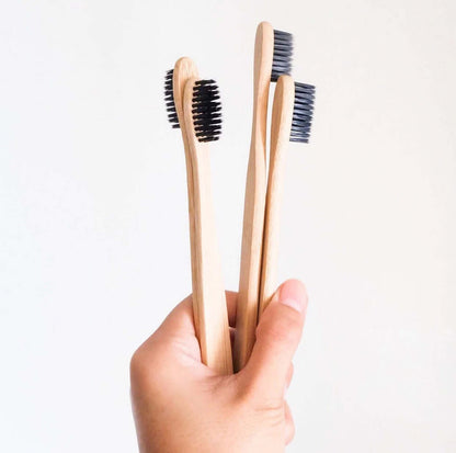 Eco-friendly bamboo toothbrushes with activated charcoal bristles held in hand for sustainable oral care.