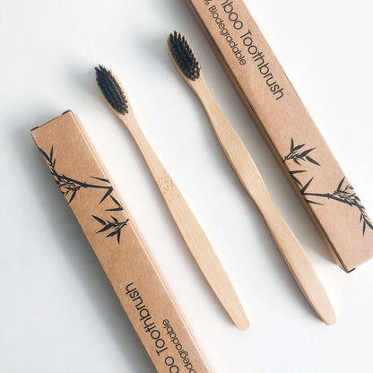 Eco friendly bamboo toothbrush with charcoal bristles in biodegradable packaging for a sustainable oral care.