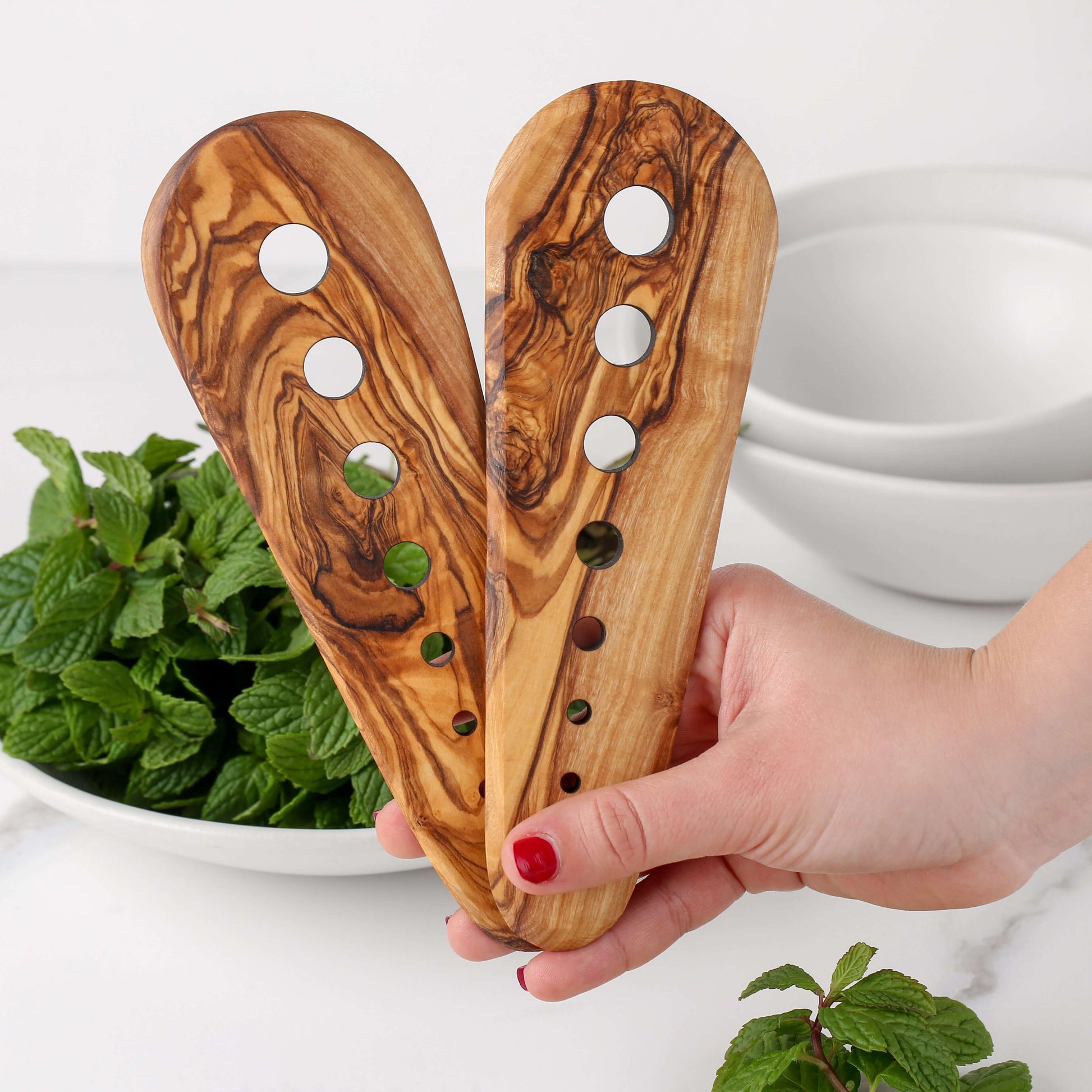 Handmade olive wood herb stripper held over fresh mint leaves, showcasing eco-friendly kitchen accessory design.