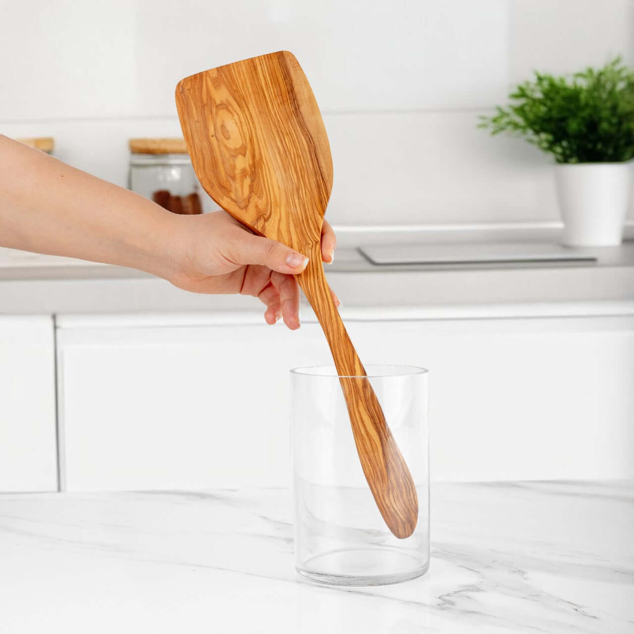 Handmade olive wood shovel spoon being used in a kitchen environment for cooking or serving.