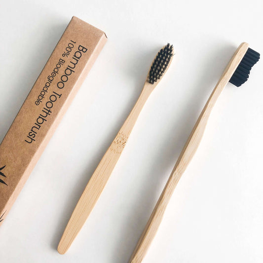 Eco-friendly bamboo toothbrush with charcoal bristles and packaging for sustainable oral care.