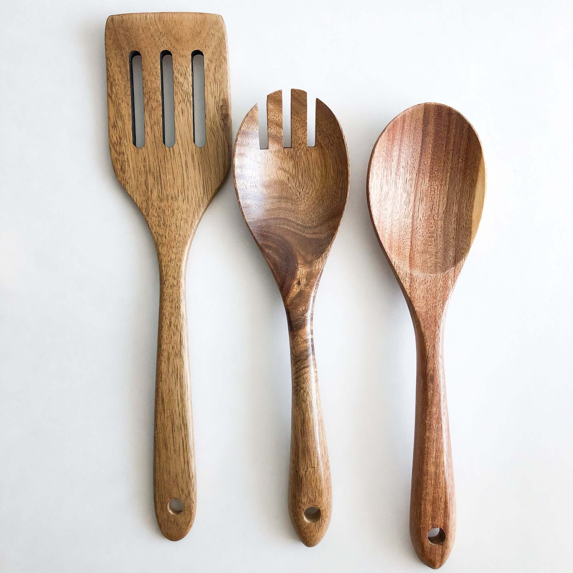 Natural acacia wood kitchen utensil set featuring a slotted spatula, serving fork, and spoon, perfect for non-stick cookware.