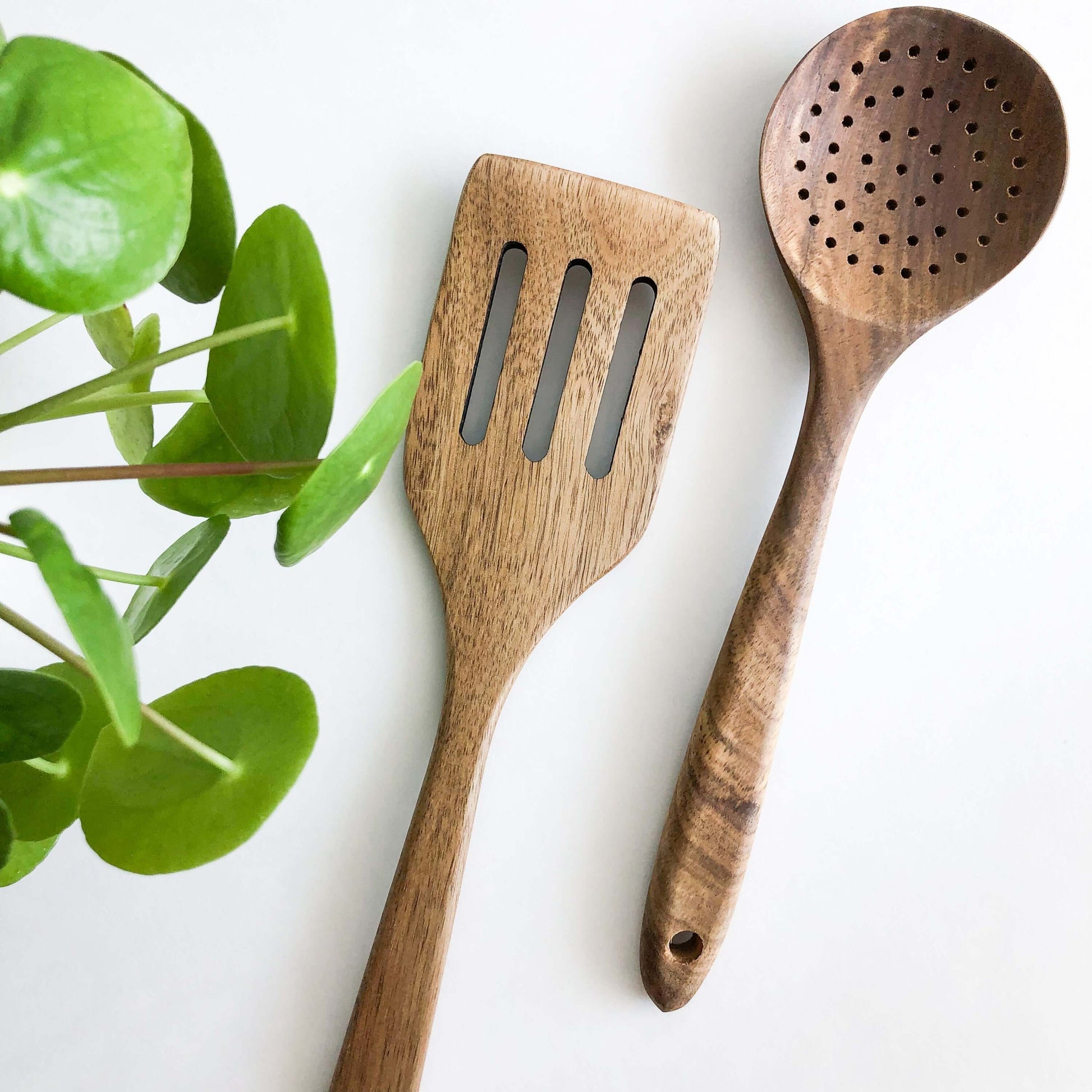 Natural acacia wood kitchen utensils including slotted spatula and skimmer, designed for non-stick cookware.