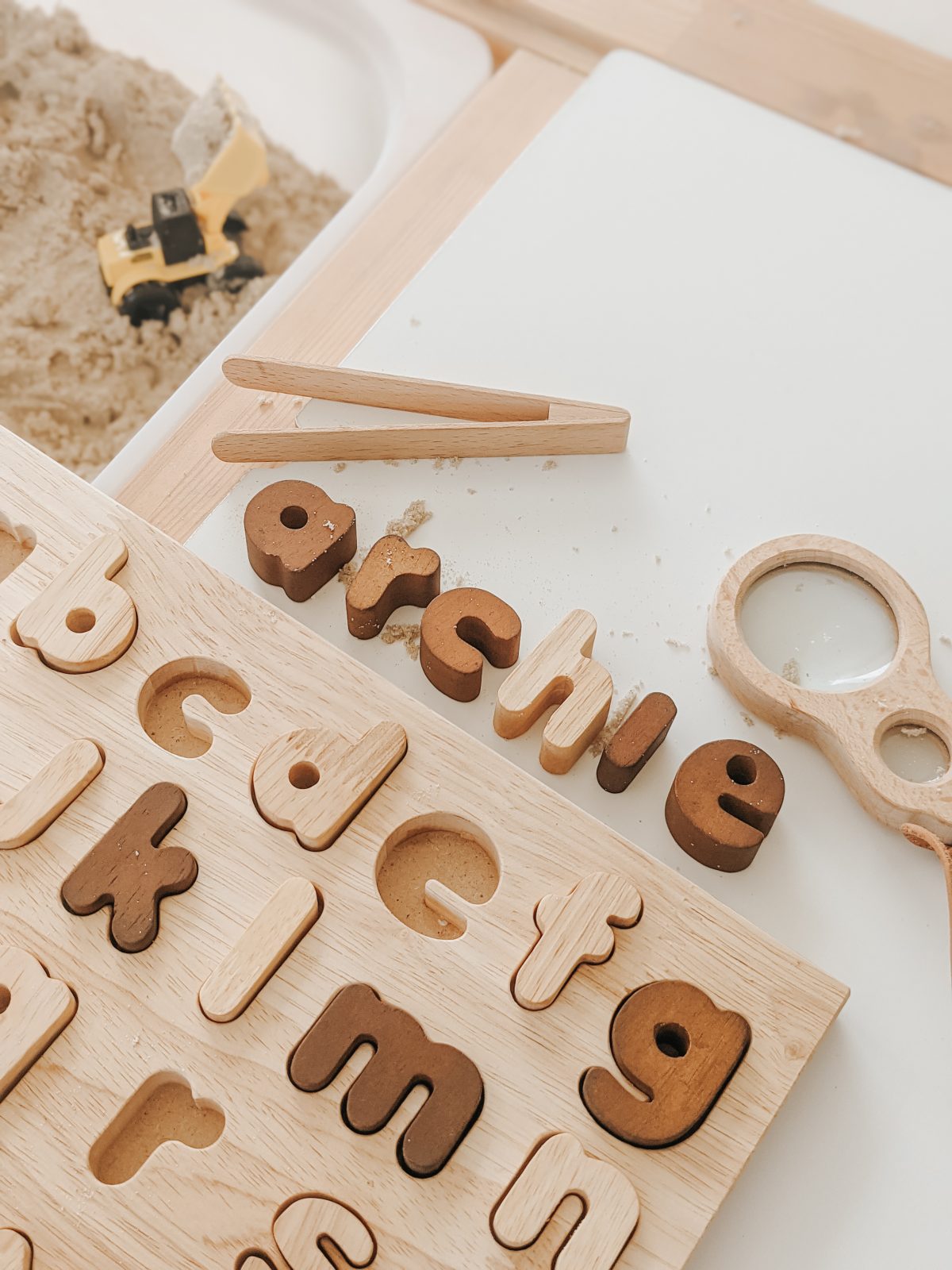 Natural lower case letter puzzle pieces arranged on a wooden board for educational play.