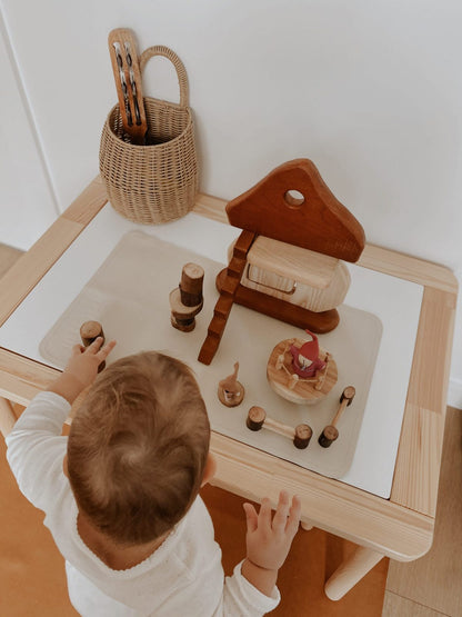 Child engaging with Natural Mushroom House imaginative play set on a wooden table, promoting creativity.