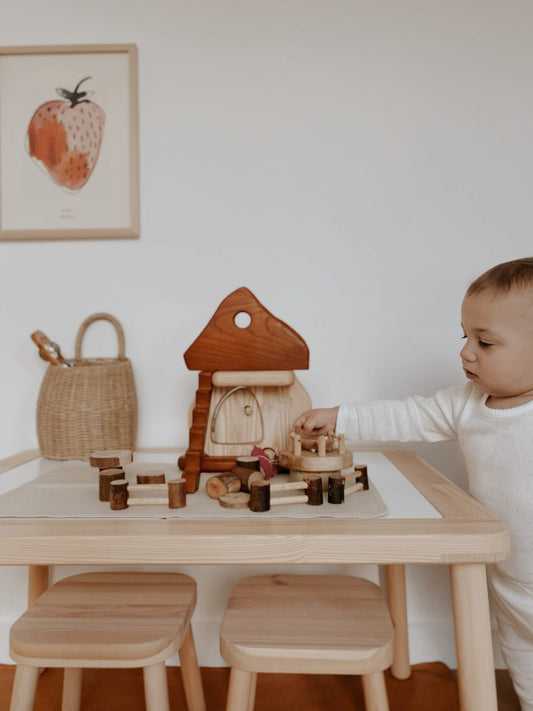 Child playing with Natural Mushroom House eco-friendly play set on table, fostering creativity and imaginative play.