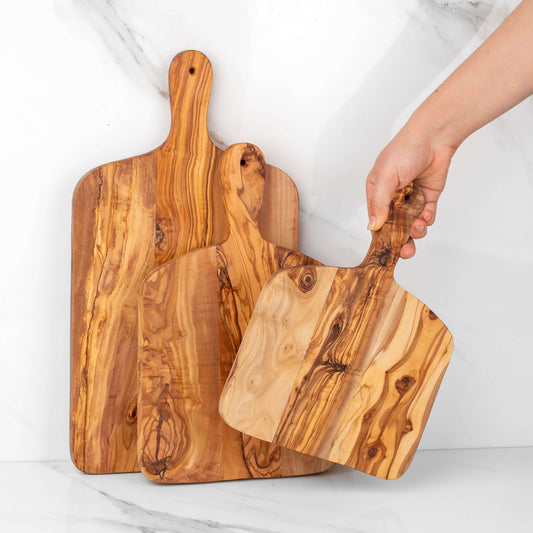 Handmade olive wood cutting boards with handles, showcasing unique grain patterns and durable design for kitchen use.