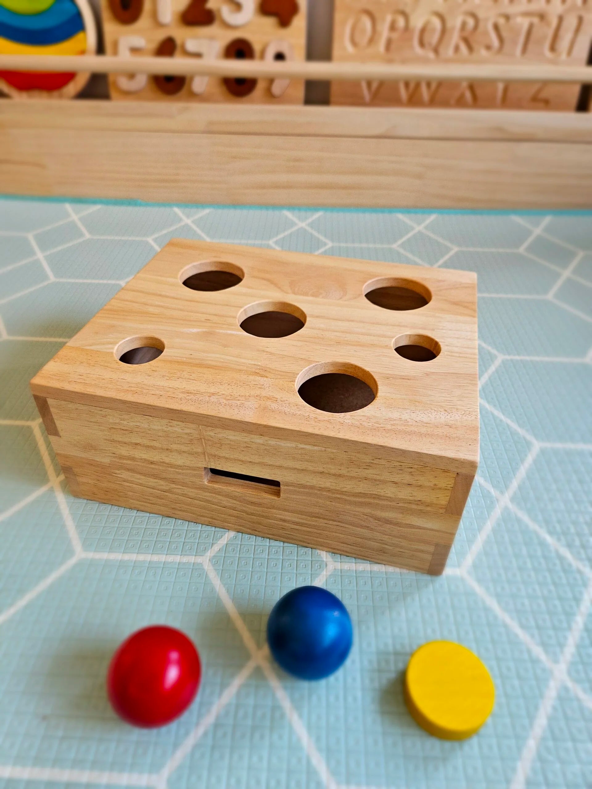 Wooden Peek-a-Boo Sorting Box with colorful balls, designed for shape and color recognition in children.