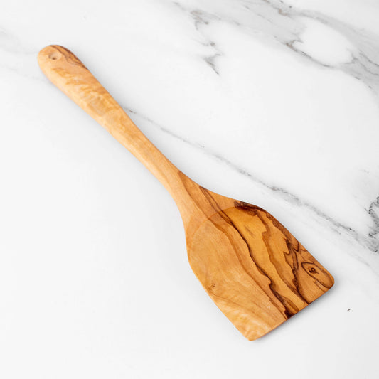 Handmade olive wood spatula on marble surface, featuring a flat head for easy flipping and stirring.