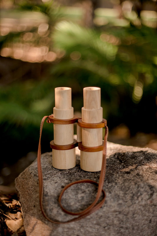 Wooden binoculars on a rock, eco-friendly adventure toy for kids, promoting imagination and observation skills.