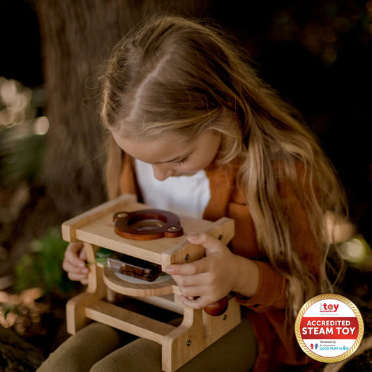 Child exploring nature with a wooden microscope, promoting scientific curiosity and eco-friendly play.