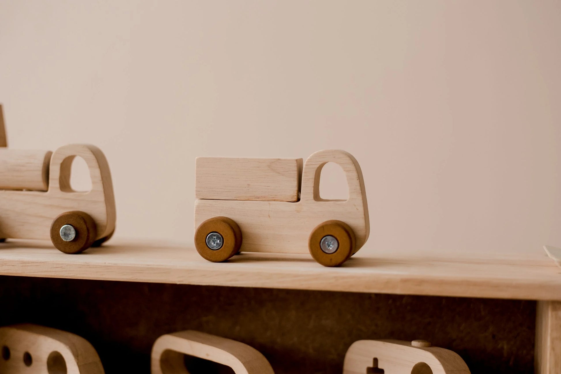 Wooden toy truck on a storage shelf, part of an imaginative vehicle play set for children.